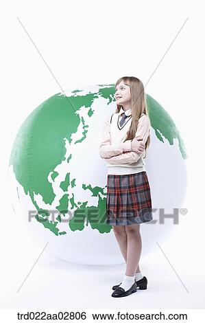 Stock Photograph - a student in uniform posing in front of a globe. Fotosearch