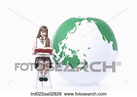 a student in uniform reading a book next to a globe View Large Photo Image Stock Photo - a student in uniform reading a book next to a globe. Fotosearch
