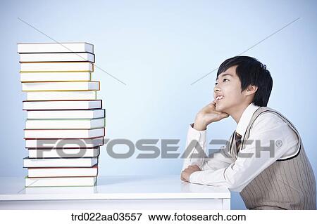 a student in uniform sitting at table with a pile of books View Large Photo Image Stock Photo - a student in uniform sitting at table with a pile of books. Fotosearch