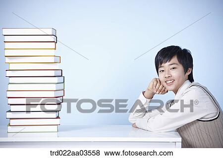 a student in uniform sitting at table with a pile of books View Large Photo Image Stock Photo - a student in uniform sitting at table with a pile of books. Fotosearch