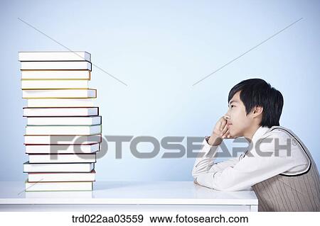 a student in uniform sitting at table with a pile of books View Large Photo Image Stock Photo - a student in uniform sitting at table with a pile of books. Fotosearch