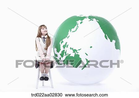 Stock Image - a student in uniform sitting on a chair next to a globe. Fotosearch