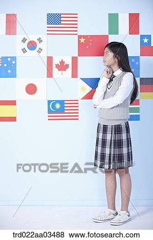 Stock Photo - a student in uniform standing in front of international flags. Fotosearch