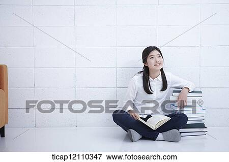 Stock Photo - a student reading a book while sitting on the floor. Fotosearch