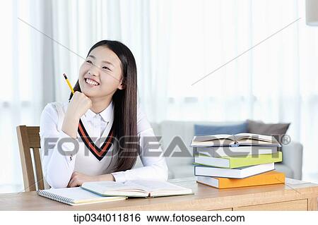 Stock Photograph - a student sitting at desk smiling. Fotosearch