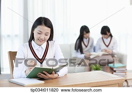 Stock Image - a student sitting at desk studying. Fotosearch
