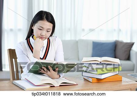 Stock Photo - a student sitting at desk studying. Fotosearch