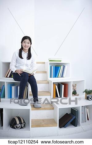 Picture - a student sitting on bookshelf . Fotosearch