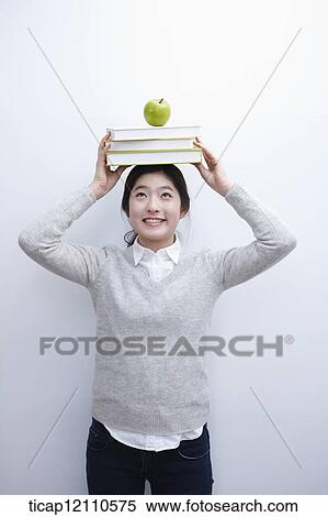 Stock Photography - a student with a pile of books on the head. Fotosearch