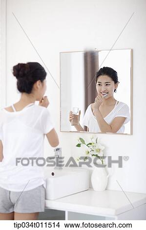 Picture - a woman brushing teeth. Fotosearch