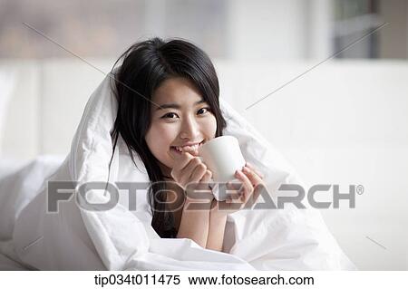 a woman drinking cup of coffee while wrapped in blanket View Large Photo Image Stock Photography - a woman drinking cup of coffee while wrapped in blanket. Fotosearch