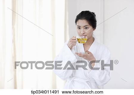 Stock Image - a woman in bathrobe drinking tea while sitting on a Jacuzzi. Fotosearch