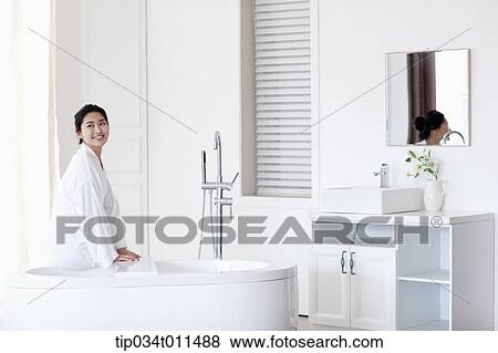 Stock Photo - a woman in bathrobe sitting on a Jacuzzi. Fotosearch