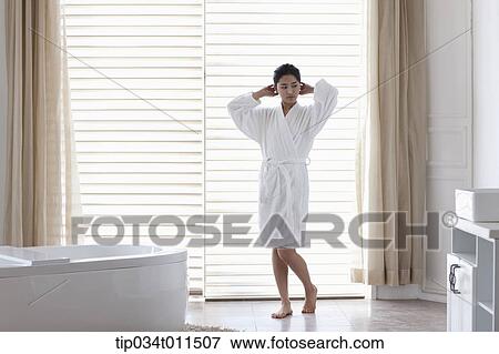 Stock Photo - a woman in bathrobe standing in a bath room. Fotosearch