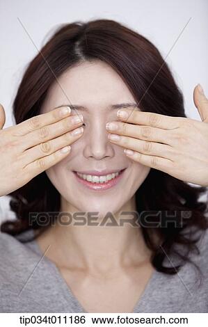 Stock Photograph - a woman in grey plain shirt covering her eyes. Fotosearch