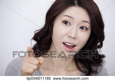 Stock Photography - a woman in grey plain shirt pointing. Fotosearch