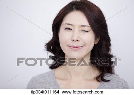 a woman in grey plain shirt winking View Large Photo Image Picture - a woman in grey plain shirt winking. Fotosearch