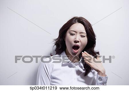 Stock Photo - a woman in white shirt fanning her mouth. Fotosearch