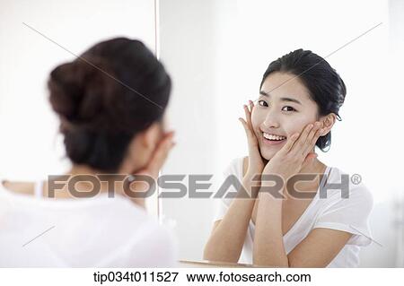 Stock Photo - a woman looking herself at the mirror. Fotosearch