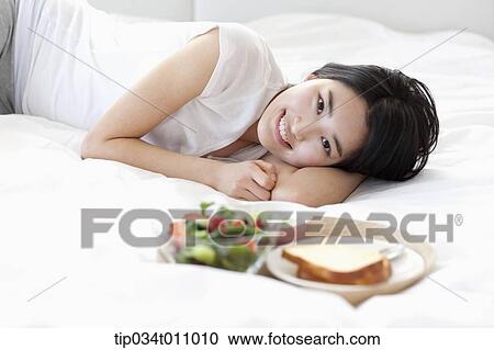a woman lying on the bed next to breakfast View Large Photo Image Stock Image - a woman lying on the bed next to breakfast. Fotosearch
