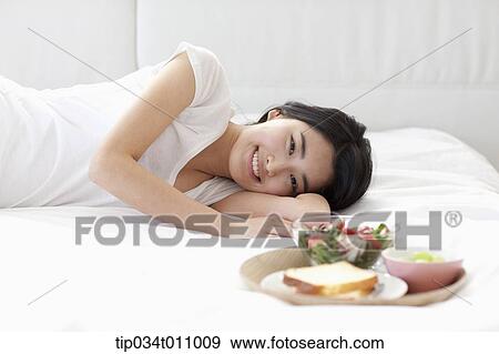 a woman lying on the bed next to breakfast View Large Photo Image Stock Photo - a woman lying on the bed next to breakfast. Fotosearch
