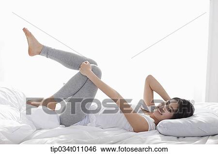 Stock Photograph - a woman lying on the bed smiling. Fotosearch