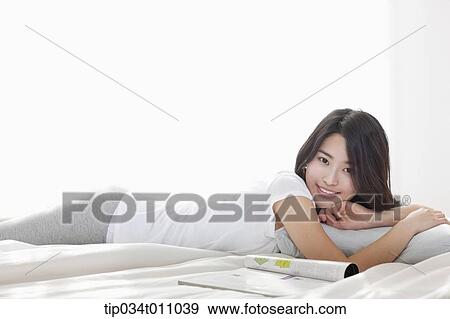 a woman lying on the bed with a magazine next to her View Large Photo Image Stock Photo - a woman lying on the bed with a magazine next to her. Fotosearch