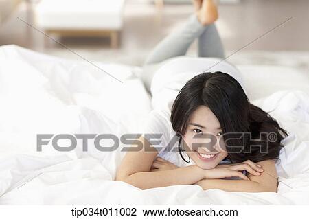 Stock Image - a woman lying on the bed with blanket. Fotosearch