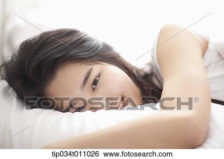 Stock Photograph - a woman on the be hugging a pillow. Fotosearch