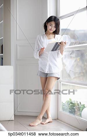 a woman reading a book leaning on the window View Large Photo Image Stock Photo - a woman reading a book leaning on the window. Fotosearch