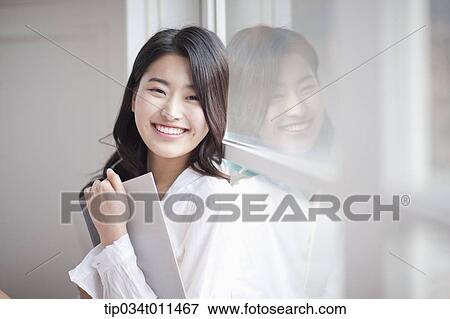 Stock Photo - a woman reading a book leaning on the window. Fotosearch