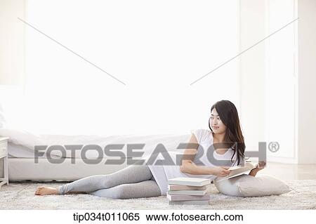 a woman reading a book lying on the floor with a pillow View Large Photo Image Stock Photography - a woman reading a book lying on the floor with a pillow. Fotosearch