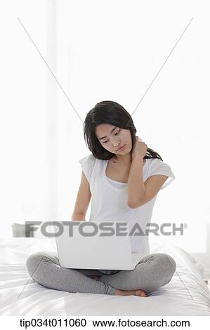 Stock Image - a woman reading a book next to a bed. Fotosearch