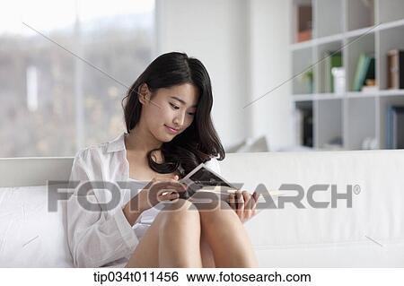 Stock Photograph - a woman reading a book on the bed. Fotosearch