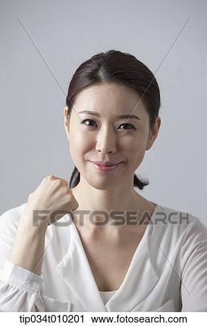 Stock Image - a woman smiling at camera while sitting at desk. Fotosearch