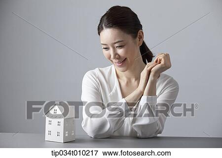 a woman smiling at desk with a small house block View Large Photo Image Stock Photo - a woman smiling at desk with a small house block. Fotosearch