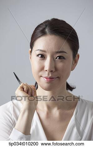 Stock Image - a woman smiling while holding a pencil. Fotosearch
