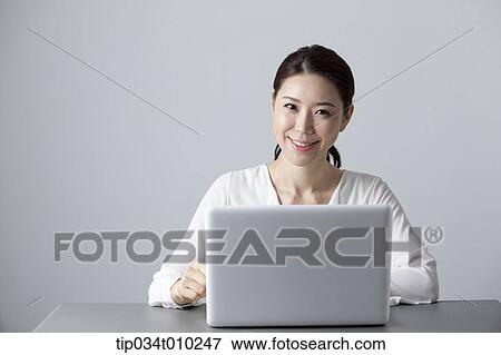 a woman smiling while using a laptop View Large Photo Image Stock Photo - a woman smiling while using a laptop. Fotosearch