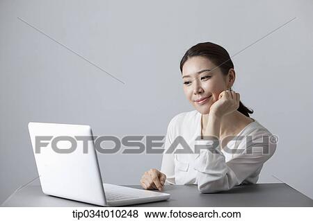 a woman smiling while using a laptop View Large Photo Image Stock Photo - a woman smiling while using a laptop. Fotosearch