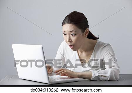 Stock Image - a woman surprised while using a laptop. Fotosearch