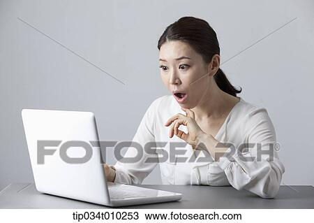 Stock Image - a woman surprised while using a laptop. Fotosearch