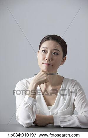 Stock Photo - a woman thinking while sitting at a desk. Fotosearch