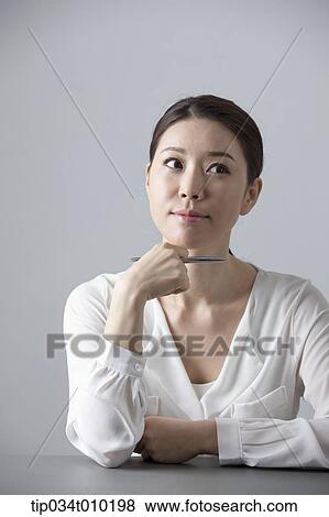 Stock Photo - a woman thinking while sitting at a desk. Fotosearch