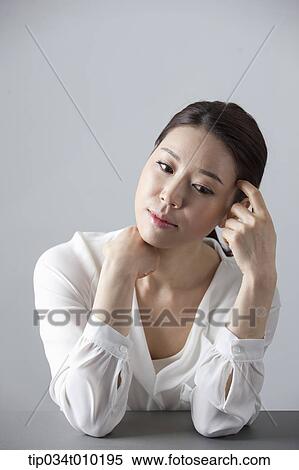 Stock Photography - a woman thinking while sitting at a desk. Fotosearch