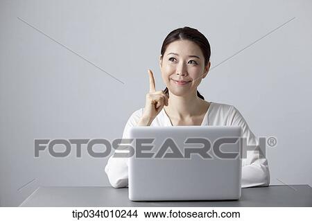 Picture - a woman thinking while using a laptop. Fotosearch