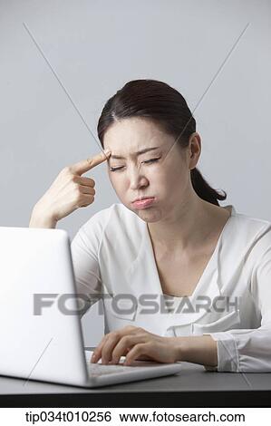 Stock Photograph - a woman thinking while using a laptop. Fotosearch