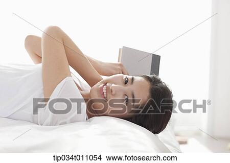 a woman with a book on the bed View Large Photo Image Picture - a woman with a book on the bed. Fotosearch
