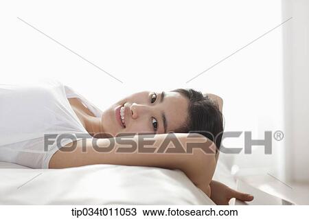Stock Image - a woman with a book on the bed. Fotosearch