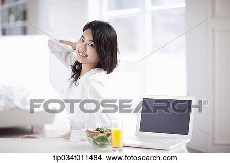a woman with a laptop with juice and salad View Large Photo Image Picture - a woman with a laptop with juice and salad. Fotosearch