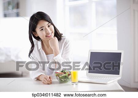 Stock Image - a woman with a laptop with juice and salad. Fotosearch